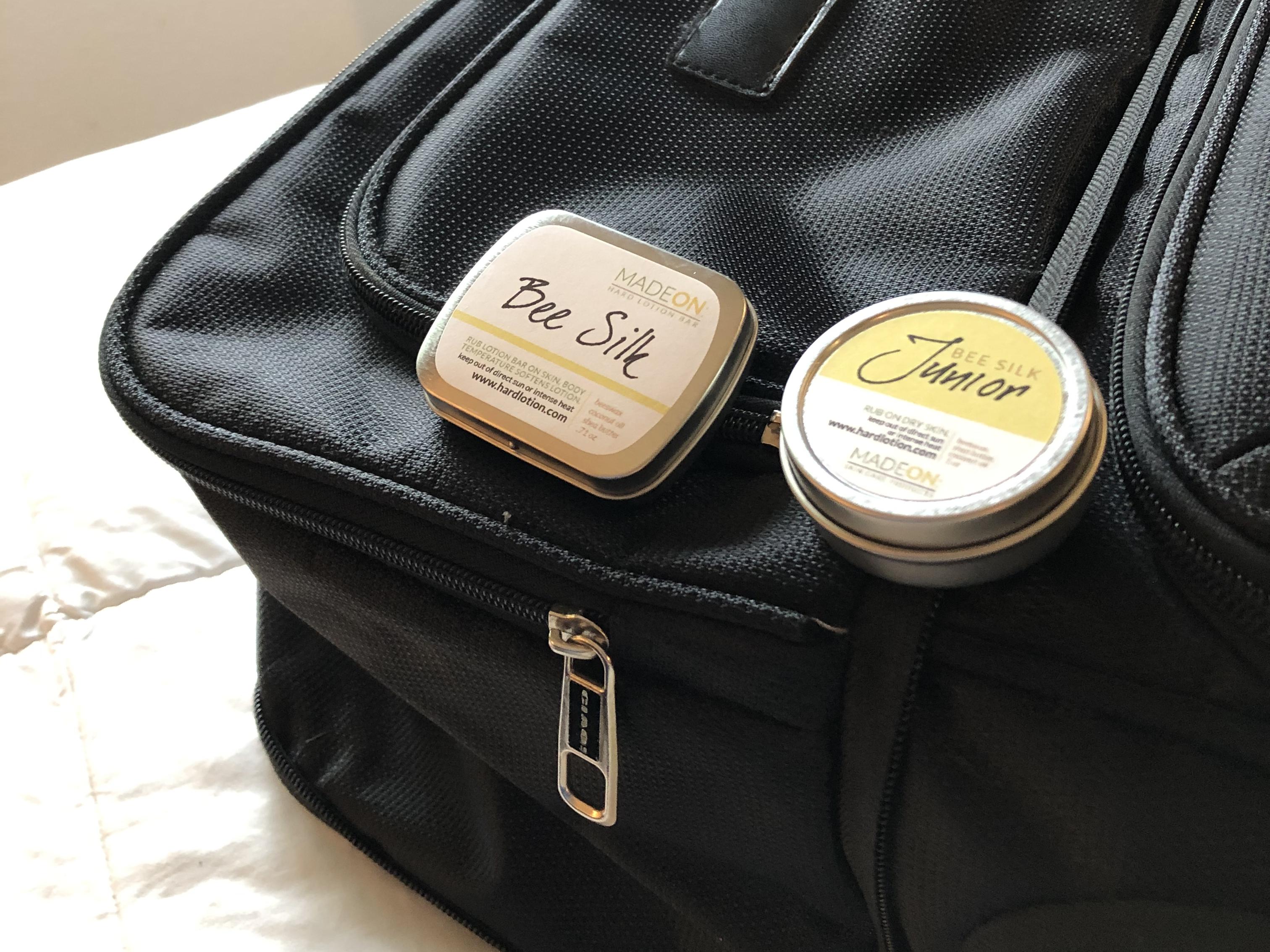 travel friendly beesilk lotion bar and emollient on a suitcase