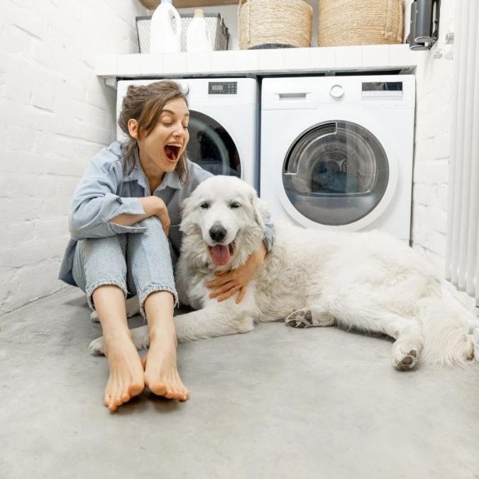 Woman and dog sitting next to washing machine