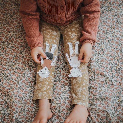 A little girl holds two paper dolls with paper clothes.