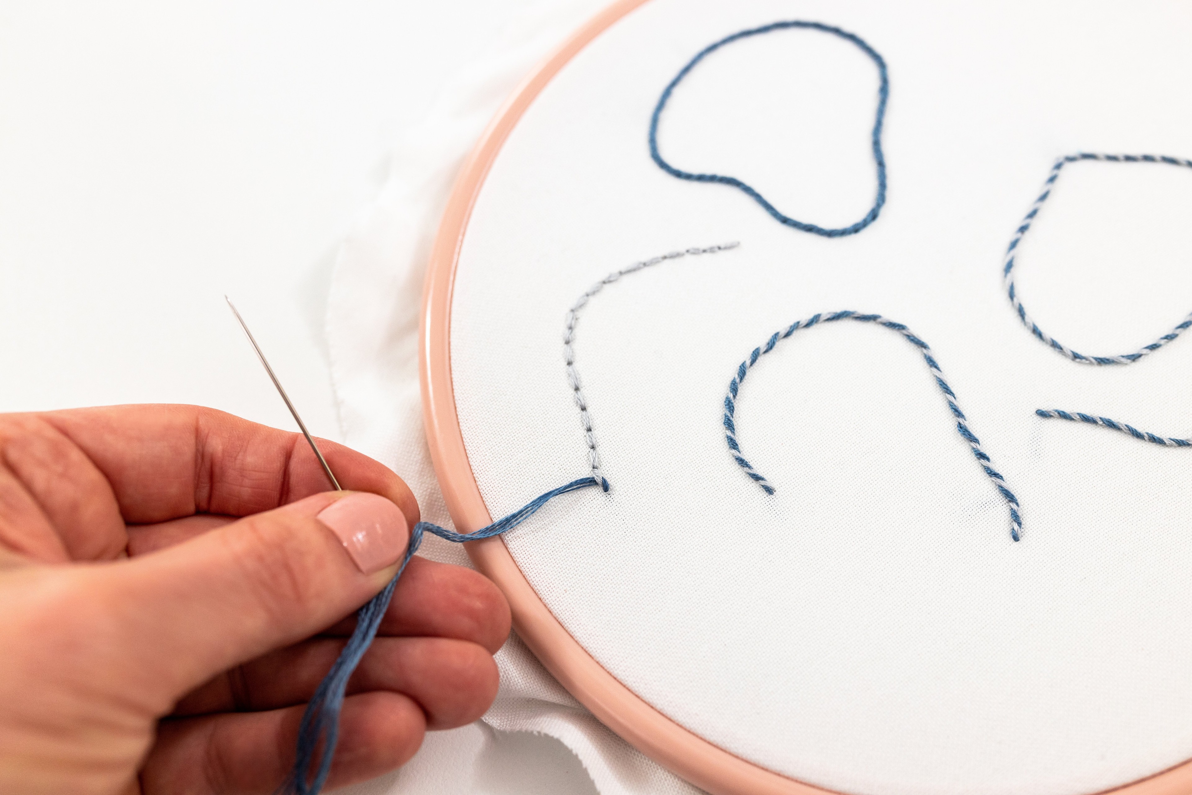 A needle is pulled tight under back stitch.