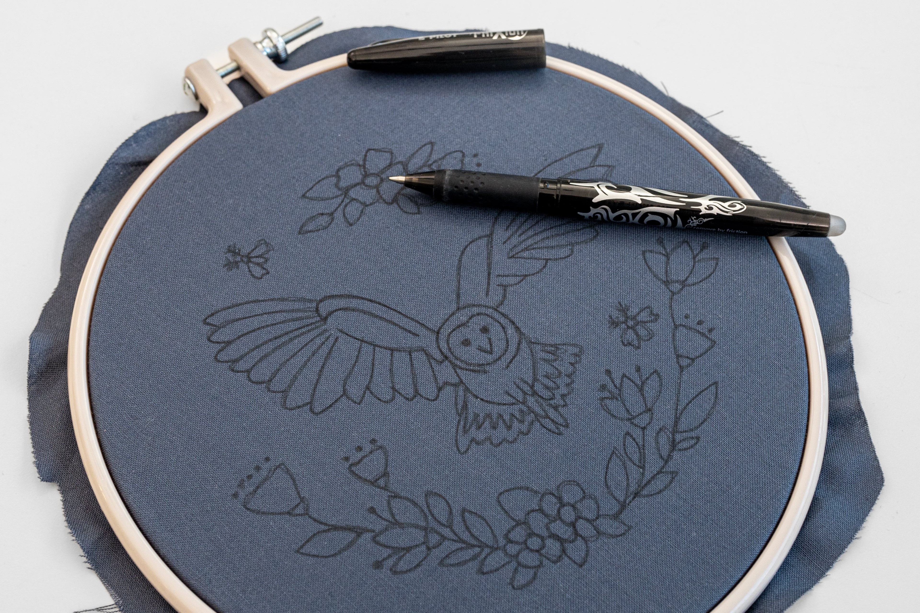 A pen lies on a fabric with 'The Night Owl' pattern drawn on it.
