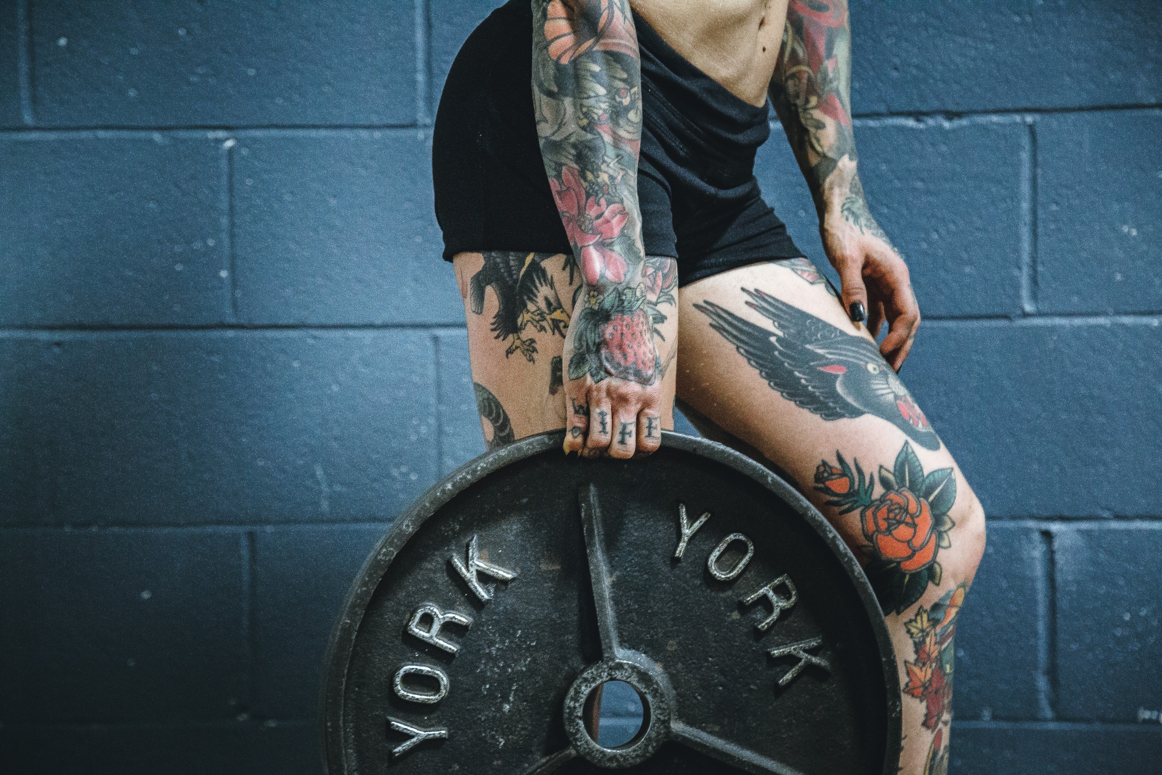tattooed girl holding weight plate