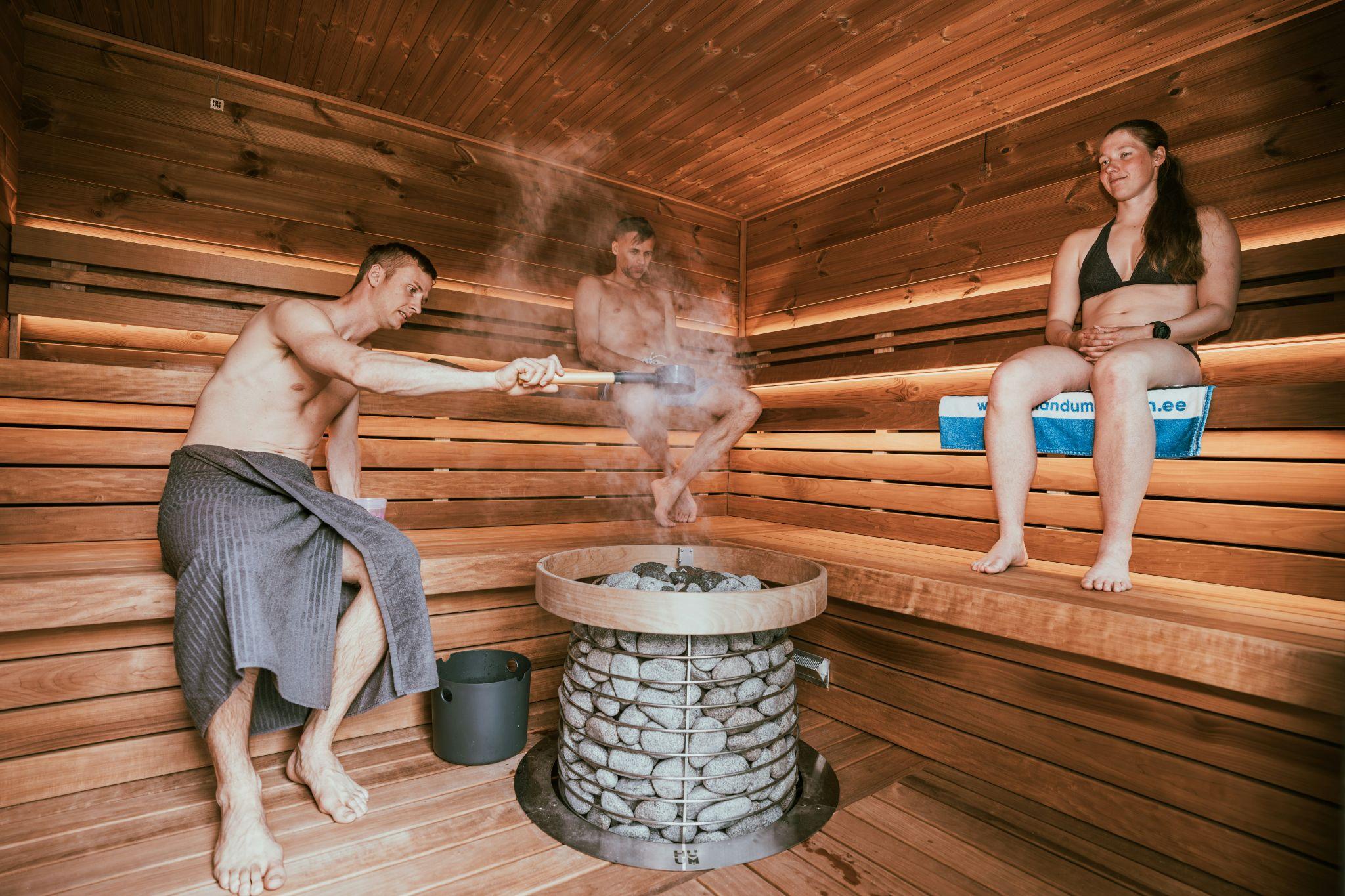 People enjoying a traditional Finnish sauna with steam rising from the sauna rocks