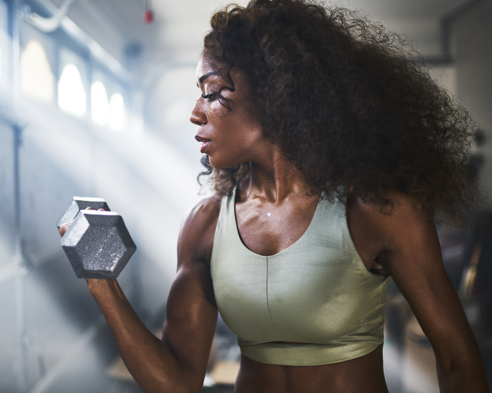 a dark skin woman holding a dumbell