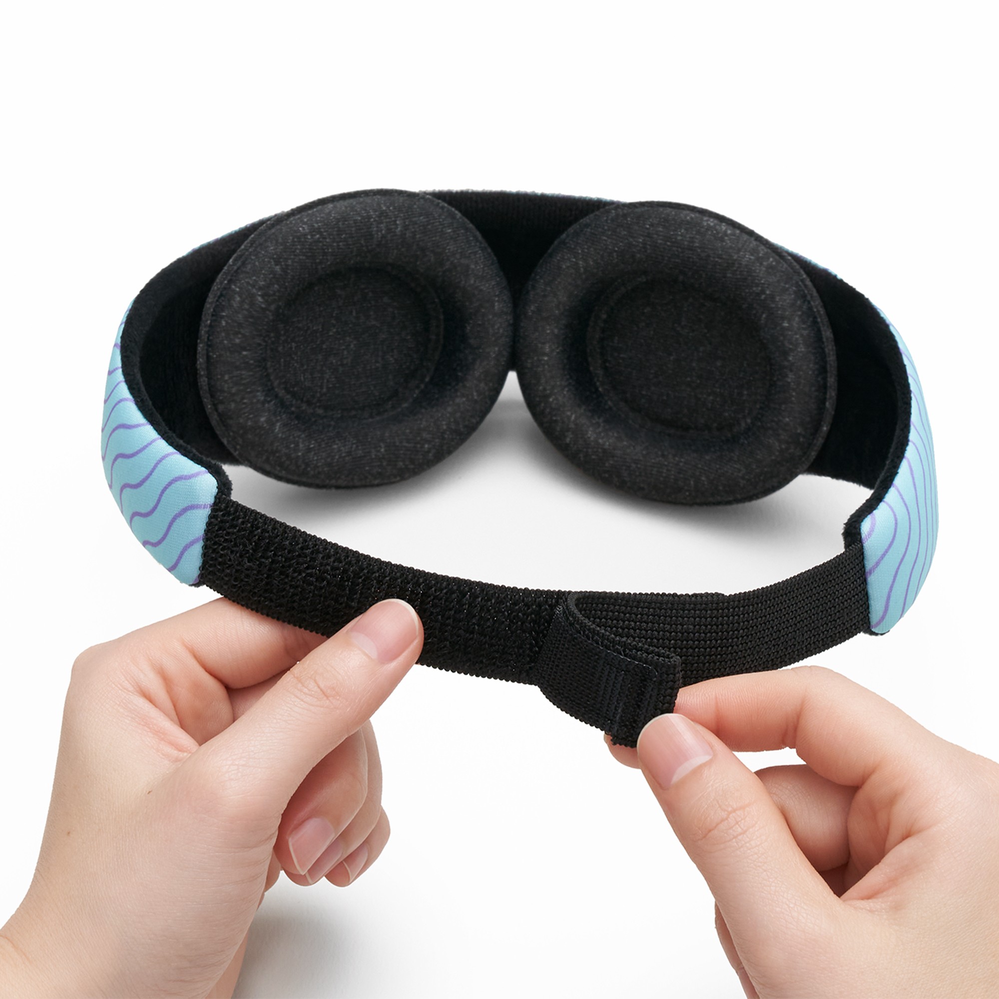 Hands demonstrating the micro hook and loop closure of a blue sleep mask for boys with eye cups.
