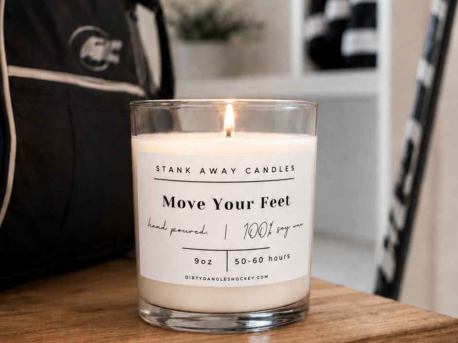 A white scented hockey candle on a wooden bench with hockey gear. Move Your Feet