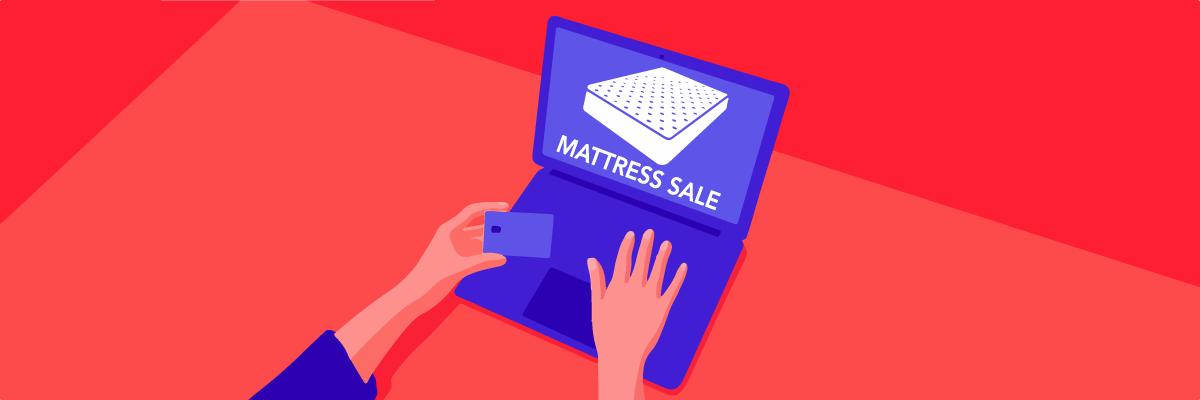 A person shopping online on a laptop. The laptop screen shows a mattress with the words mattress sale.