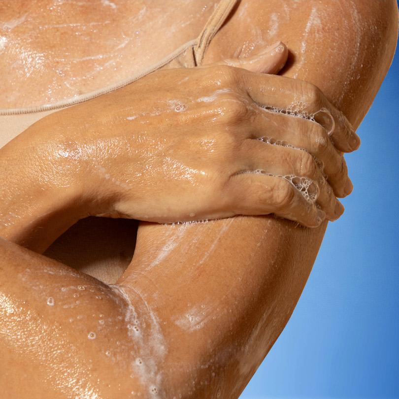 1. The hands appear to be gently massaging or scrubbing the skin, indicating the use of this skincare product.