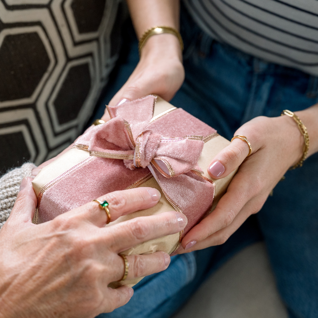 A pink jewellery case with gold jewellery