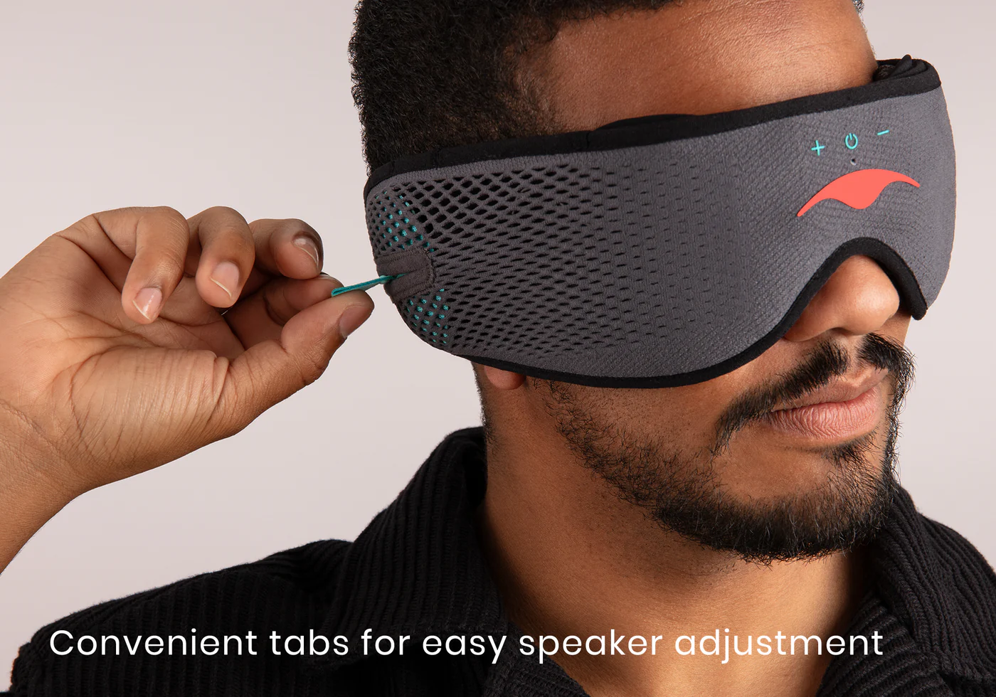 A man tugging the tab of a speaker inside a gray Bluetooth® sleep mask for sound and sleep.