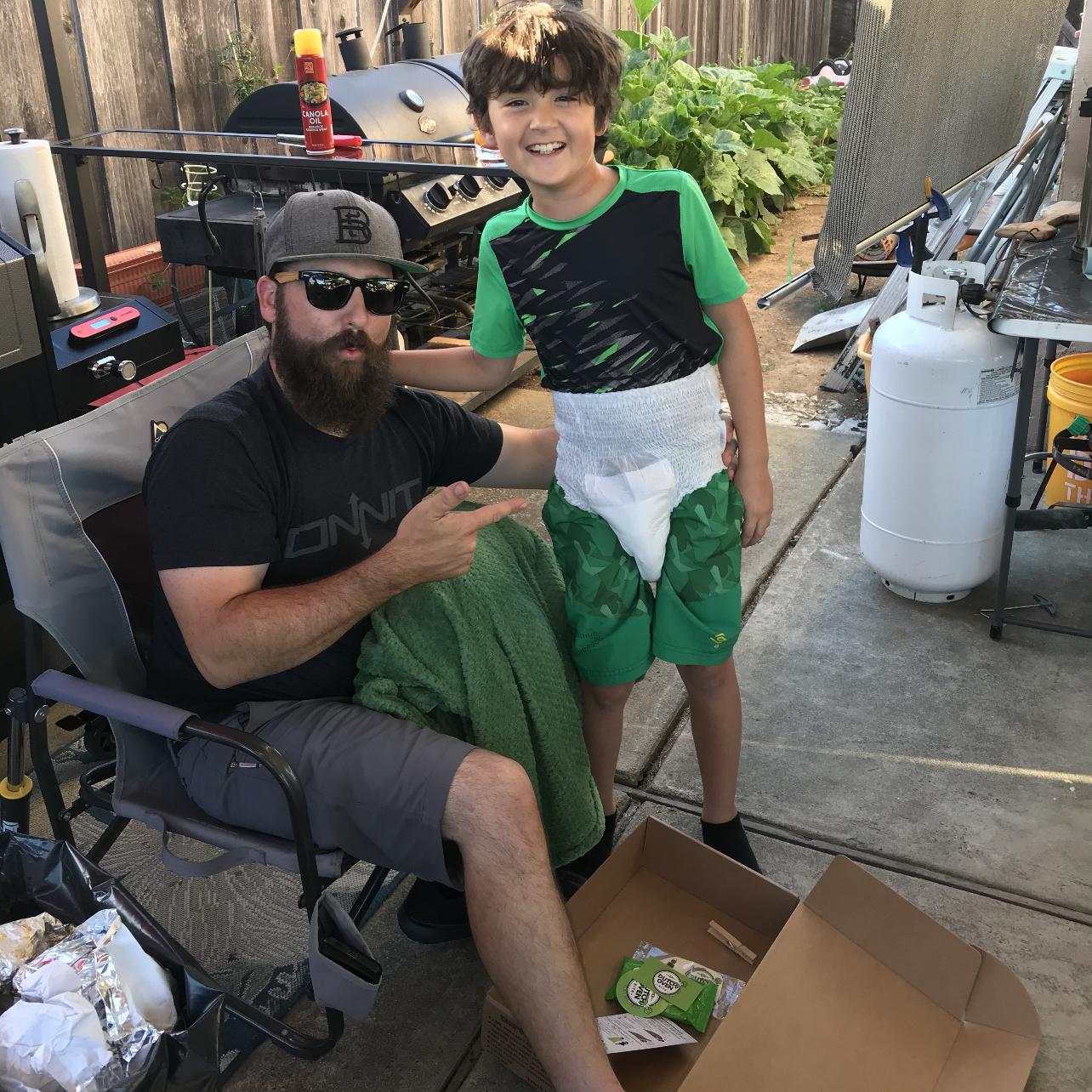 A man opening a blue dutch oven kits gift box and laughing