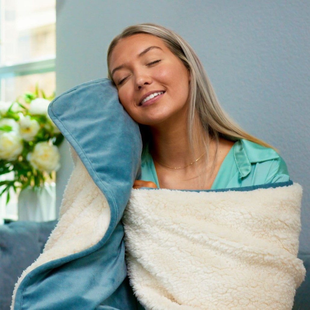 A woman snuggled up in a Potty Buddy Waterproof Blanket