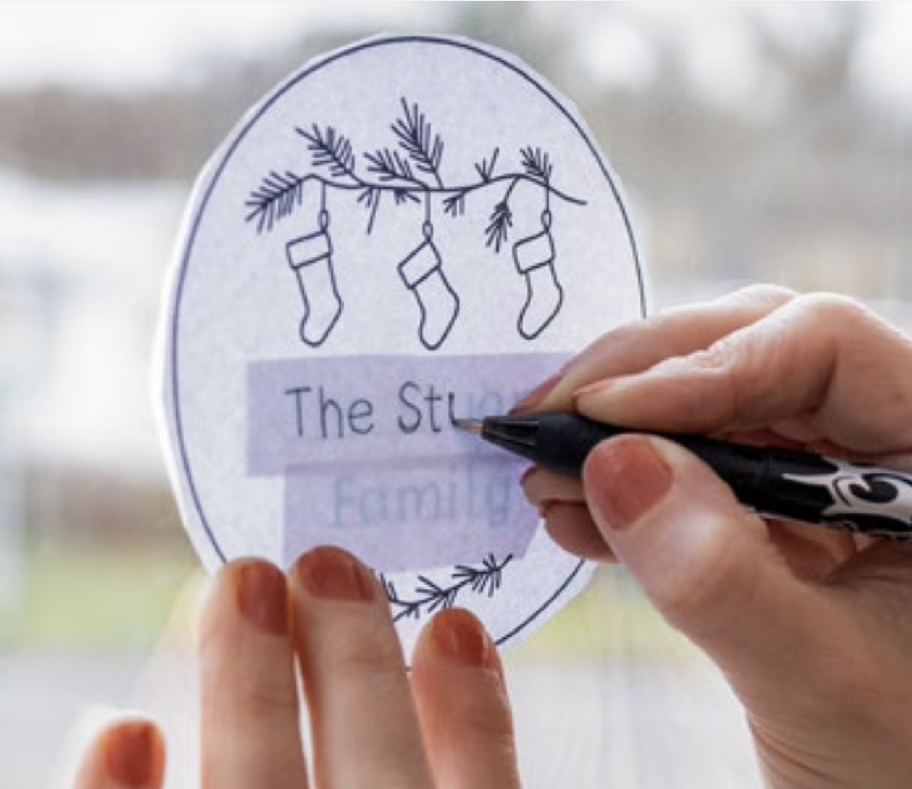 Hands draw on the words 'The Stuart Family' onto a patttern.