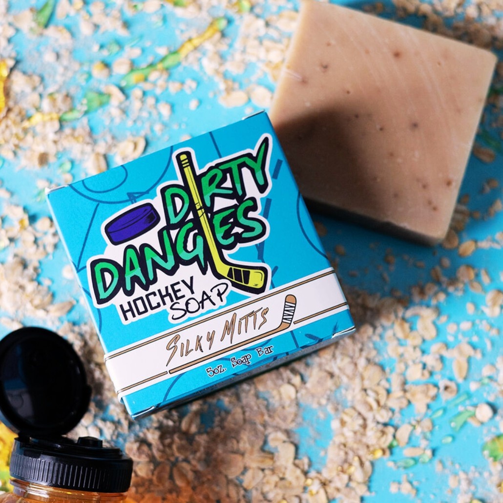 A brown bar of dirty dangles hockey soap on a blue background with oats and honey