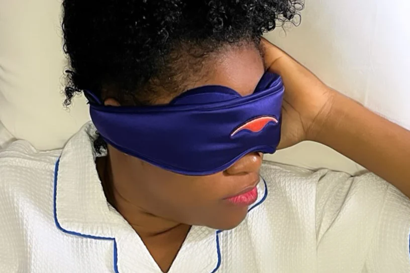 A woman wearing a blue silk sleep mask with eye cups that’s good for the skin.