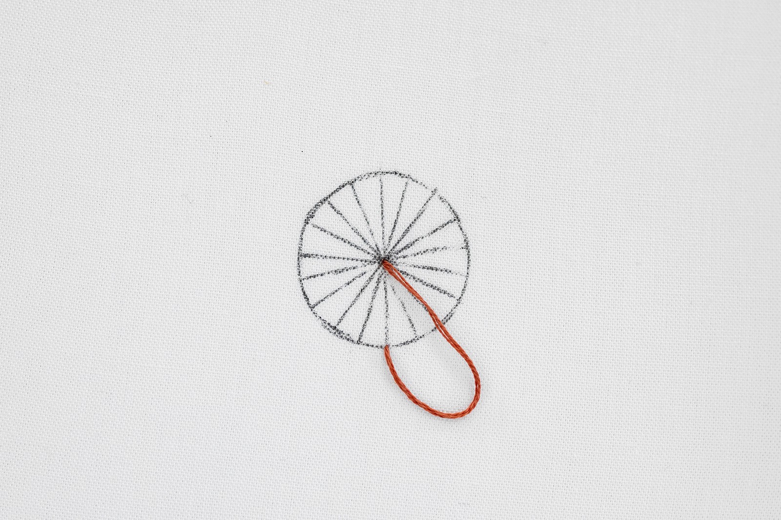 A thread goes through the middle of a drawing of a wheel.