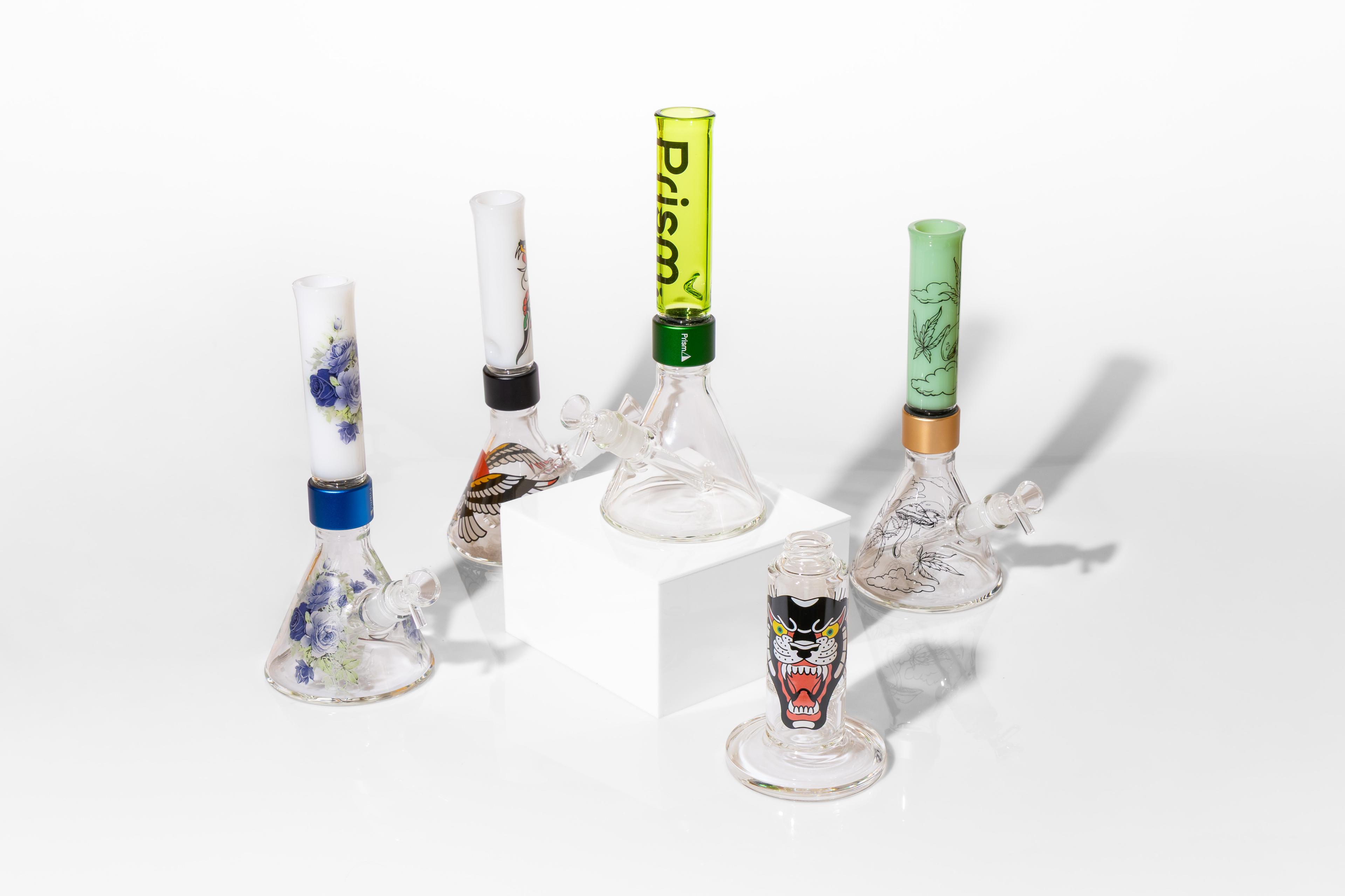 Assorted Prism MINI custom bongs featuring honeycomb, straight, and beaker base styles. The modular glass pieces display vibrant kiln-fired decal artwork from the Inked, Moonlight Rose, and Pretty Done collections against a clean white background.