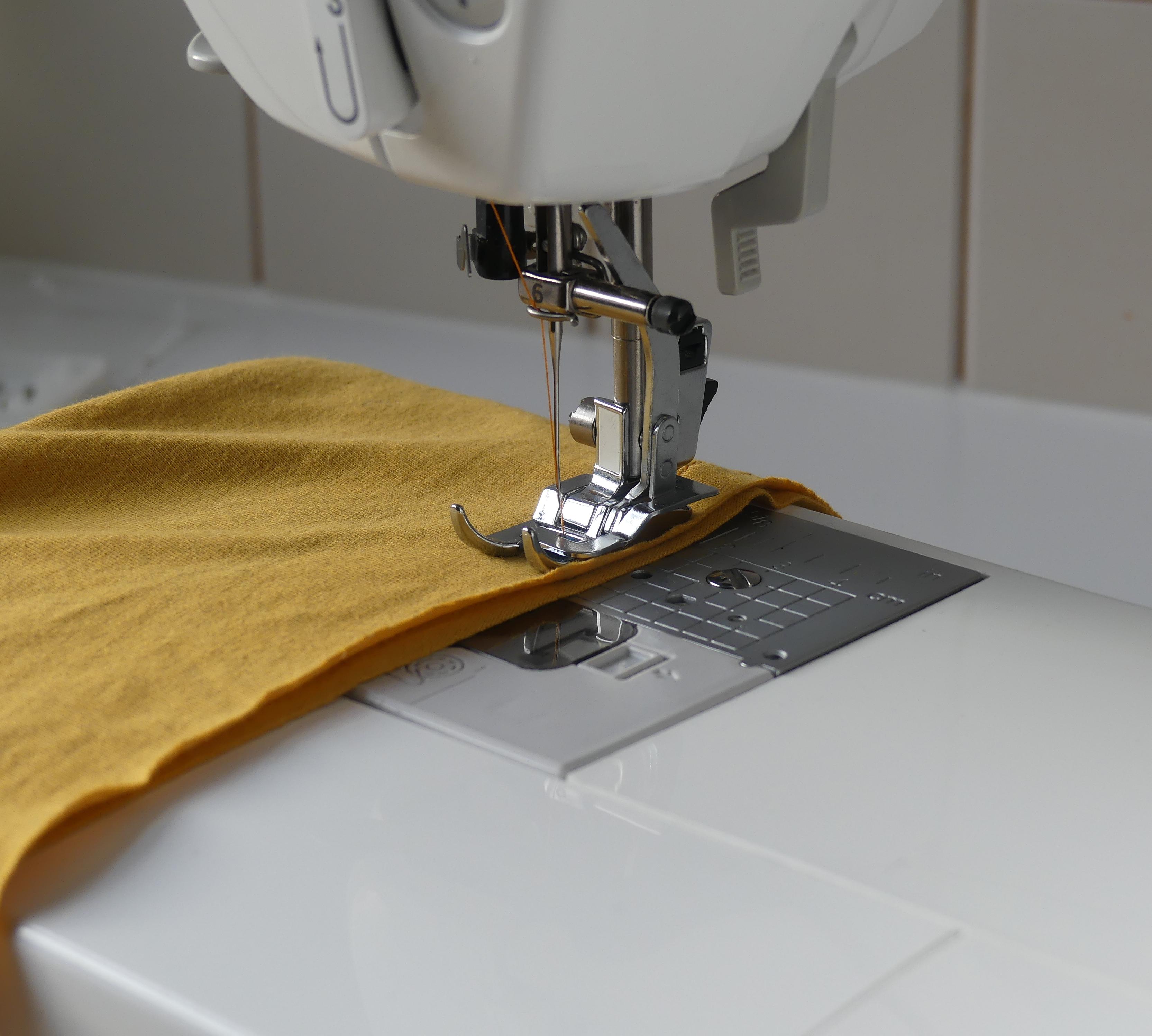 Knit foot on a sewing machine with yellow fabric