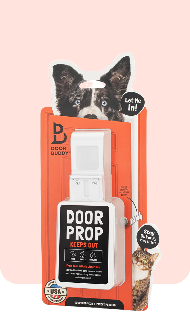 Door Buddy Door Prop retail packaging displayed with a dog illustration saying Let Me In and a cat graphic saying Stay Out of My Kitty Litter. The packaging highlights the door prop designed to keep dogs out of litter box areas while still allowing cats to enter and exit the room.